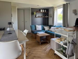 a living room with a blue couch and a table at Chalet Oostkapelle in Oostkapelle