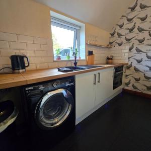 eine Küche mit Waschmaschine und Spüle in der Unterkunft Swallow cottage in Howden