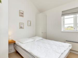 a white bedroom with a bed and a window at 4 star holiday home in Nysted in Nysted