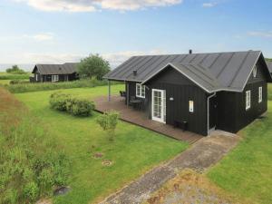 een zwart huis met een terras in een veld bij Holiday home near Nysted in Nysted