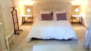 a bedroom with a white bed with purple pillows at LAMATHYE in Aramon