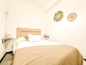 a white bedroom with a large bed with a blanket at Apartamento Susurros do Atlántico by ALÔGA in Fisterra