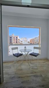 Una mesa y dos sillas en una habitación con ventana. en Apartamento Playa Gran Tarajal, en Gran Tarajal