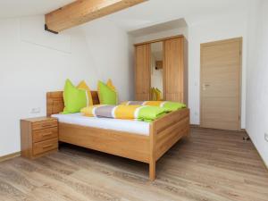 a bedroom with a bed with green and orange pillows at Traumhaftes Feriendomizil für Familien in Ellscheid +30 photos