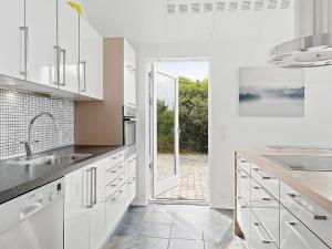 a kitchen with white cabinets and a large window at 5 star holiday home in Blokhus in Blokhus