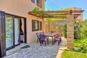 a patio with a table and chairs under a pergola at Apartment Villa Dolce Vita in Premantura +30 photos