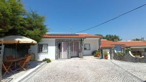 a white house with an umbrella and a patio at Casa Machuca - espaço exclusivo com piscina in Tomar