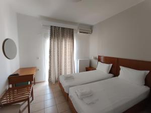 a hotel room with two beds and a desk at Stavros Beach Hotel in Stavros