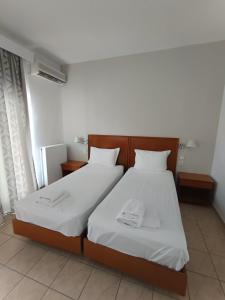 a bedroom with two beds with white sheets at Stavros Beach Hotel in Stavros