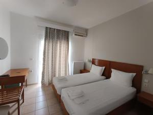 a hotel room with two beds and a desk at Stavros Beach Hotel in Stavros