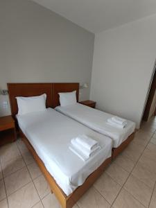 a bedroom with two beds with white sheets and towels at Stavros Beach Hotel in Stavros