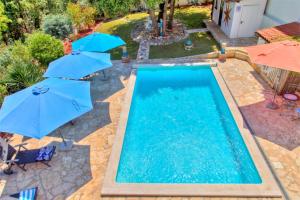 a swimming pool with two blue umbrellas next to it at Apartment Villa Dolce Vita in Premantura
