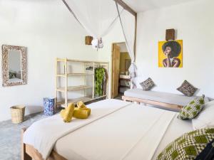 two beds in a room with white walls at BONDENI BEACH HOUSE in Jambiani