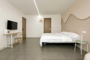 上海市にあるXiangwang Hotel Shanghai Airport 24H Free Shuttleのベッド、机、テレビのある寝室