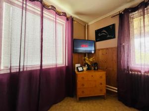 a living room with purple curtains and a tv at Gamla Posten Huset in Ytterhogdal