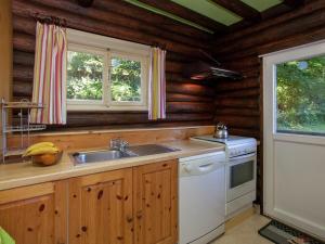 a kitchen with a sink and a stove and two windows at Cozy Chalet in Francorchamps in Francorchamps