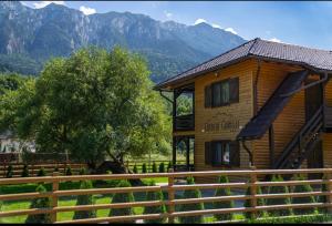 a log cabin with a tree and mountains in the background at Apartamente Creasta Craiului in Zărneşti +33 photos