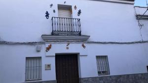 un edificio bianco con balcone e porta di Casa rural ocaña a La Puebla de los Infantes