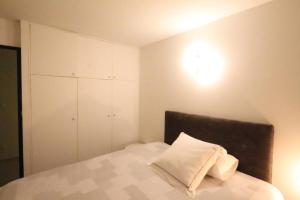1 dormitorio con 1 cama con sábanas blancas y armario en Chambre proche Montmartre, en París