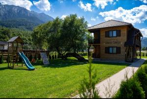 a playground in front of a house with a slide at Apartamente Creasta Craiului in Zărneşti