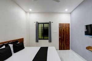 Un dormitorio con una cama y una ventana y una puerta. en Hotel O Vaidehi, en Rāipur