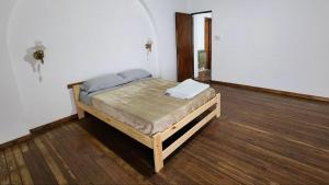 a bed in a room with a wooden floor at La casa de la abu in Carmen de Areco
