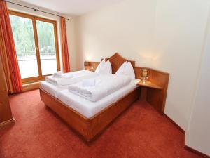 a bedroom with a bed with white sheets and a window at Chalet in Saalbach near Ski Lift in Saalbach Hinterglemm