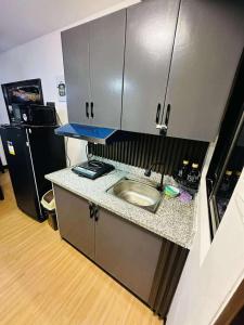 Una pequeña cocina con fregadero y refrigerador. en Reyes Haven - Urban Deca Marilao, en Marilao