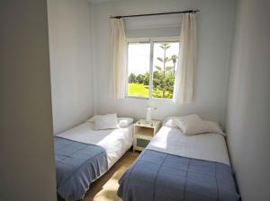 two beds in a room with a window at Vista al Mar con Terraza - Costa Ballena Apartamento primera linea de playa in Costa Ballena