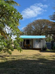 a small white house with a blue tin roof at Tilakaz Kreol in Pointe d'Esny