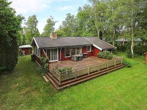 a red house with a wooden deck in the yard at 4 person holiday home in Vejby in Vejby +46 photos