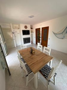 a dining room with a wooden table and white chairs at Mare fuori in Villasimius