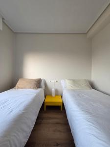 two beds in a room with a yellow table between them at Casa frente al mar in Valdoviño