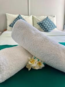 a rolled up towel on a bed with flowers at Tikaban in Pointe d'Esny