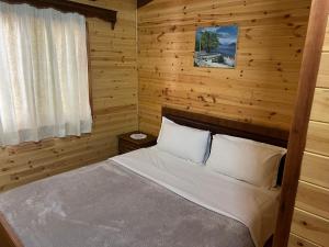 a bedroom with a bed in a wooden cabin at Bujtina Uji I Panjes, LLOGARA in Vlorë