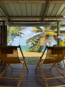 two chairs on a deck with a view of the beach at Tilakaz Kreol in Pointe d'Esny