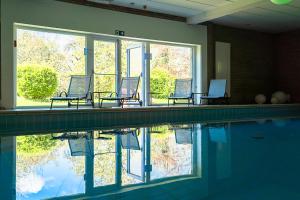 a swimming pool with two chairs next to the water at Hotel Le Beau Séjour in Nassogne