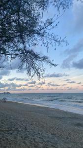 a beach with people standing on the sand and the ocean at Homestay Kuala Terengganu By Aminah in Kuala Terengganu +8 photos