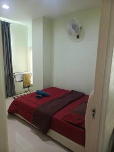 a bedroom with a bed with a red blanket and a fan at Homestay Petron Cabang 3 in Kota Bharu