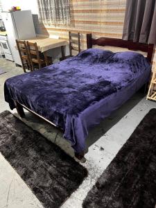 a bed with a purple blanket on top of it at Mahaidana Kitnet in São Thomé das Letras
