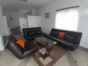 a living room with a black leather couch and a glass table at Vila Gunša in Šipovo