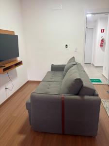 a gray couch in a living room with a flat screen tv at Apartamento próximo ao Hospital de Amor in Barretos