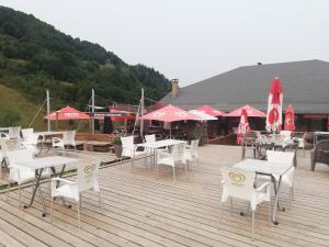 a group of tables and chairs and umbrellas on a deck at Studio chaleureux de montagne in Ustou
