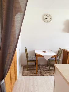 una mesa y sillas en una cocina con reloj en la pared en Apartmán v Trutnově, en Trutnov
