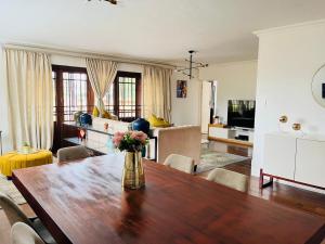 a living room with a wooden table with a vase of flowers at Petalsoft in Pretoria
