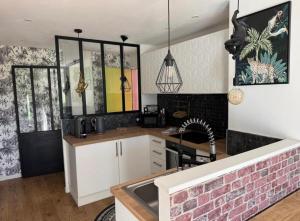a kitchen with white cabinets and a brick wall at Le petit nid douillet in Saint-Herblain