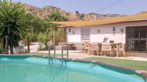 a house with a swimming pool and a table at Casita Naranja in Alora