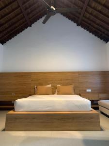 a bedroom with a large bed with a wooden headboard at Lullaby Bungalows in Uluwatu