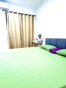 Rizku Homestay Port Dickson 4 Bedroom 4 Bathroom في باسير بانجانغ: غرفة نوم بسرير اخضر ونافذة