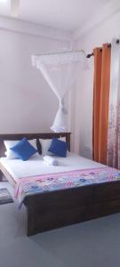 1 dormitorio con cama con dosel y almohadas azules en Villa AP, en Hikkaduwa